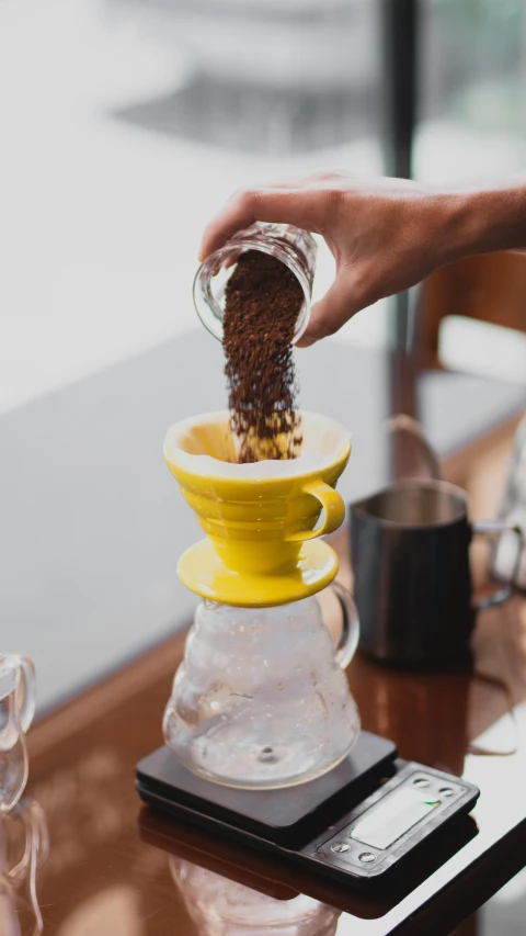 someone pours a cup of coffee into a drip pot