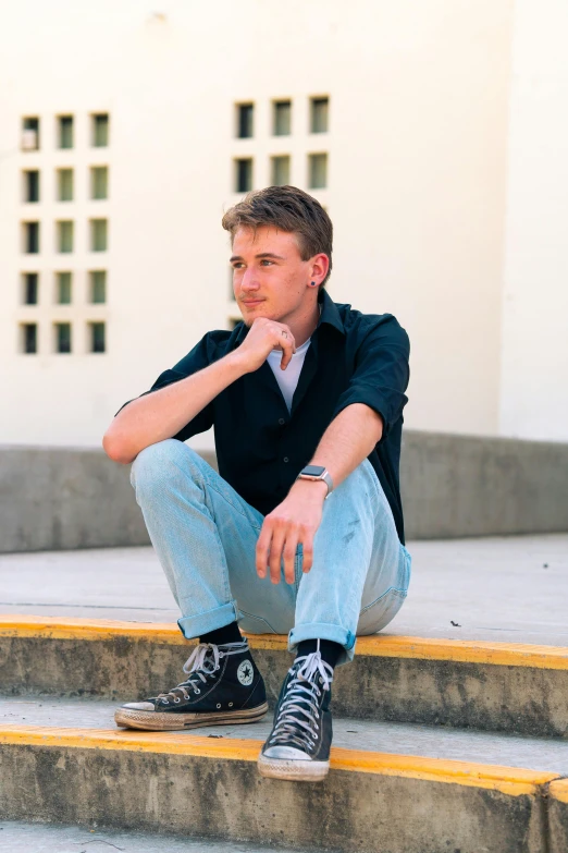 a young man is sitting on the steps outside