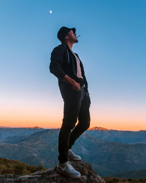 a man standing on top of a rock in the mountains