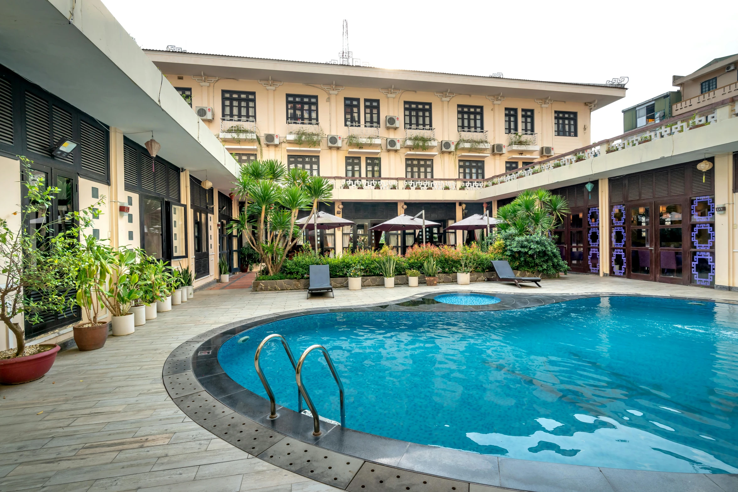 the view of a large swimming pool with plants surrounding it