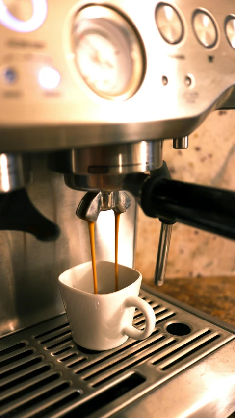 espresso machine dropping coffee into cup filled with liquid