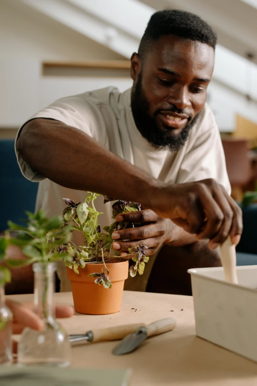 a man standing next to a table holding a plant