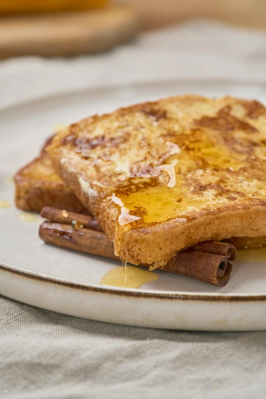 a plate with cinnamon french toast and two cinnamon sticks sticking out