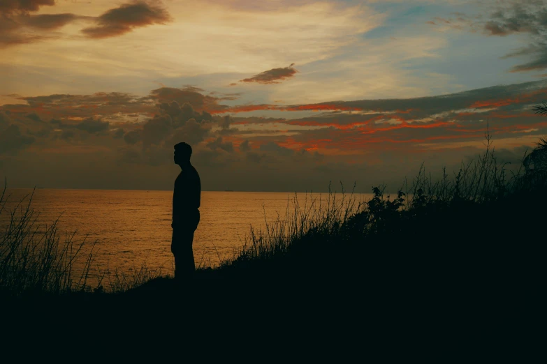 a person standing on top of a hill next to water