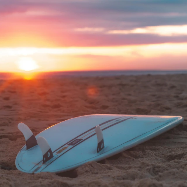 the sun is setting over a white surfboard