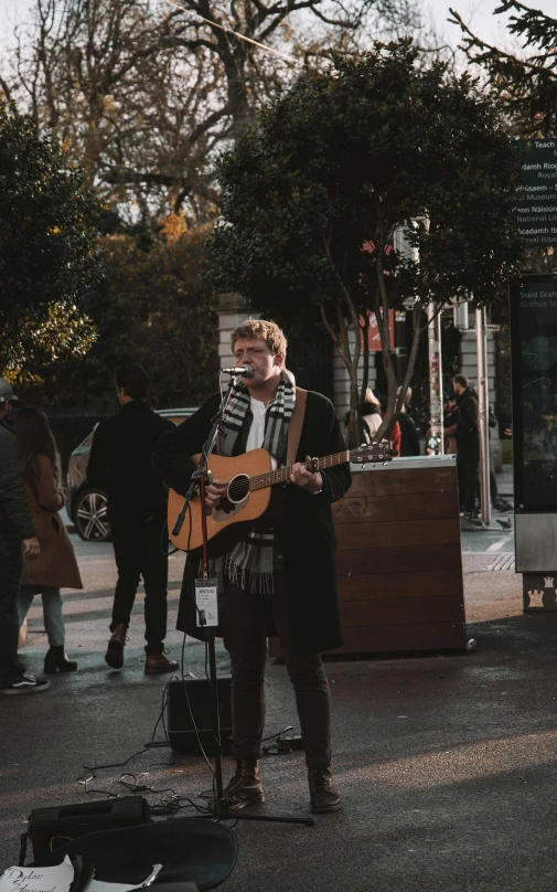 a man is playing the guitar in the street