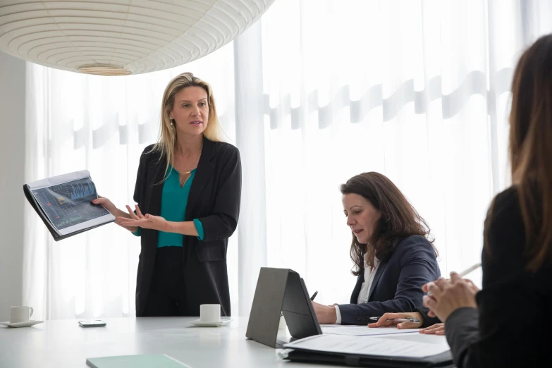 a woman stands behind a table with three laptops