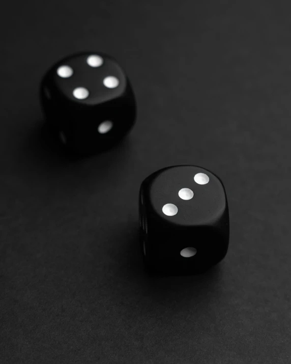 two dices laying side by side on a black surface