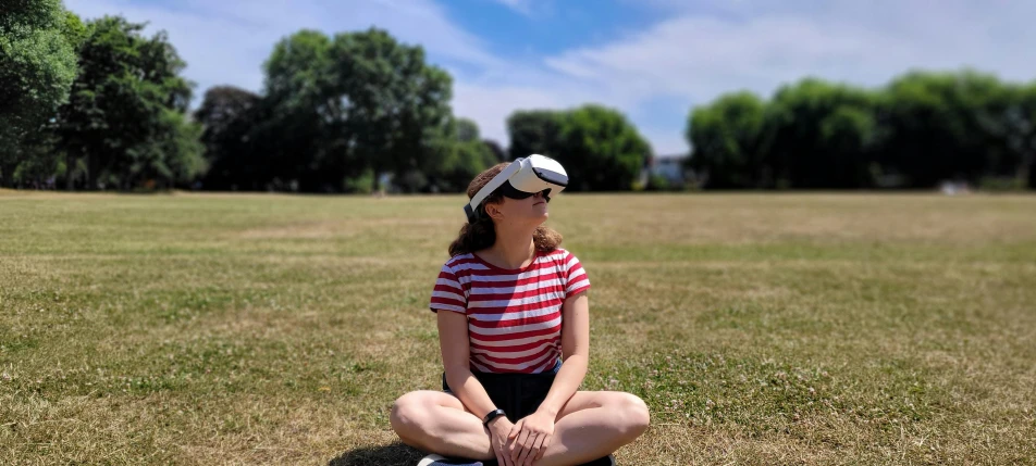 there is a woman sitting on the grass and looking at the sky