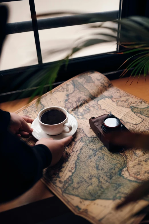 a person holding a cup of coffee next to a map