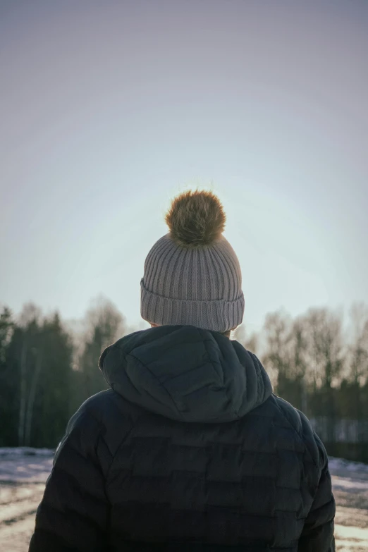 a person in winter clothing standing looking at trees