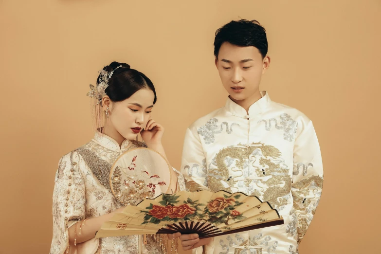 a couple in traditional clothing holding a fan