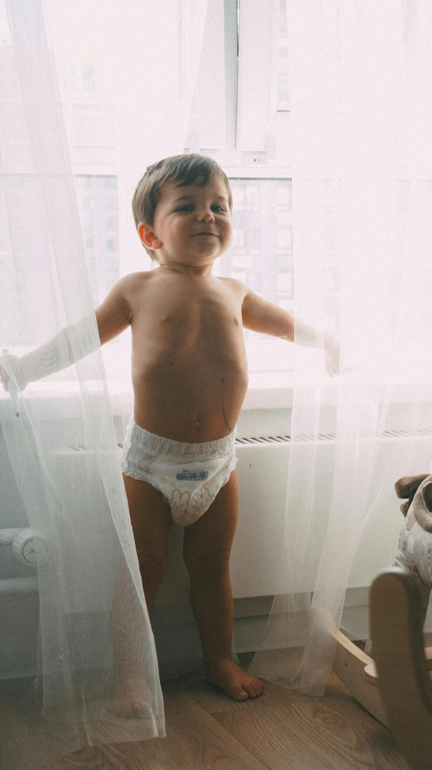 a boy in diapers holding his arms up