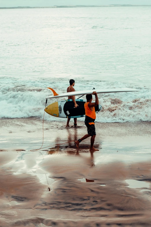 two boys are holding up surfboards on the beach