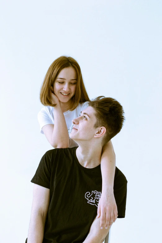 young man sitting on chair with teenage girl standing near them