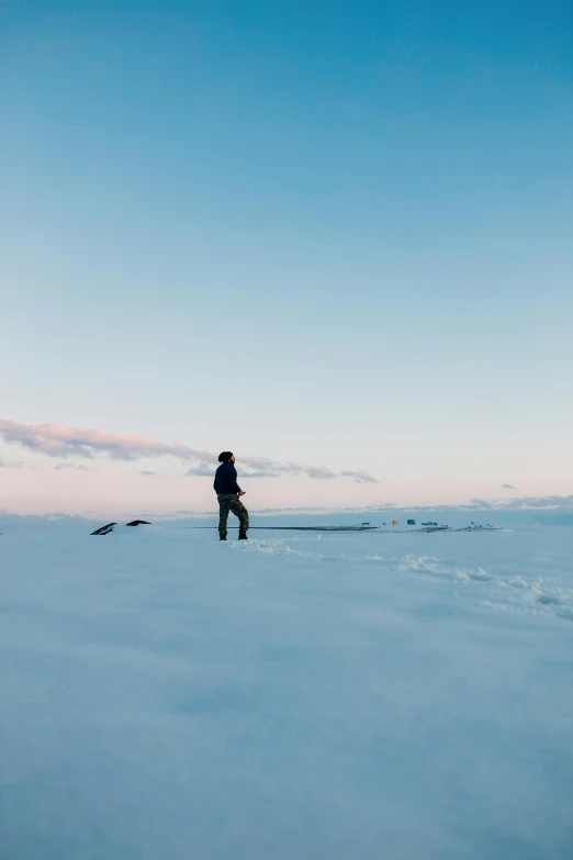 a man standing in the snow, facing away from the camera