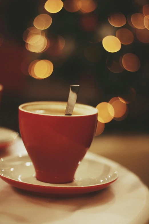 a red cup of coffee on a table with a small knife sticking out of it