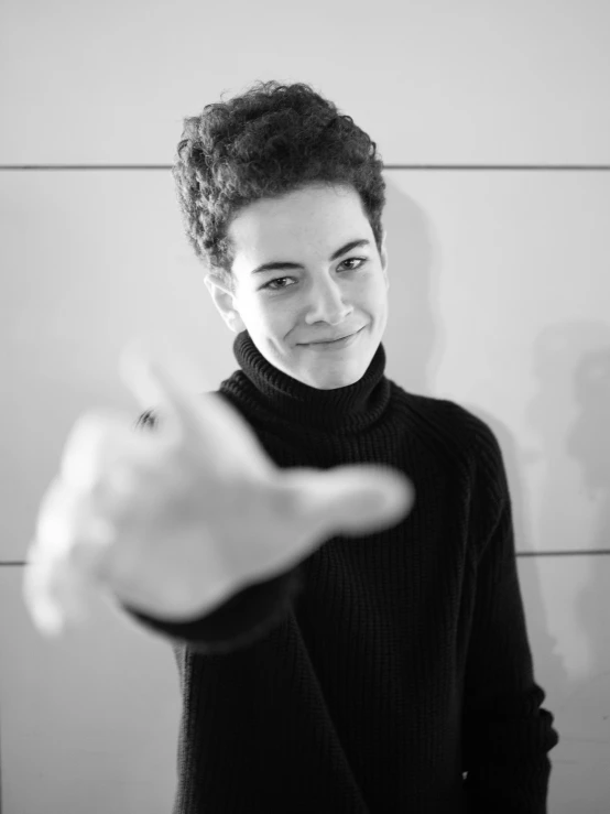 young man wearing black clothing and holding up hand