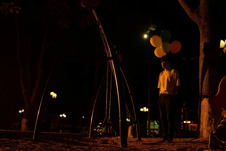 a man holding several balloons with lights in the background