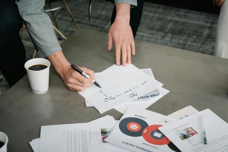 a person holding a pen is putting a small amount of paper into a cup