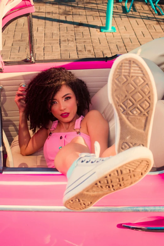 a beautiful young lady laying in a pink car