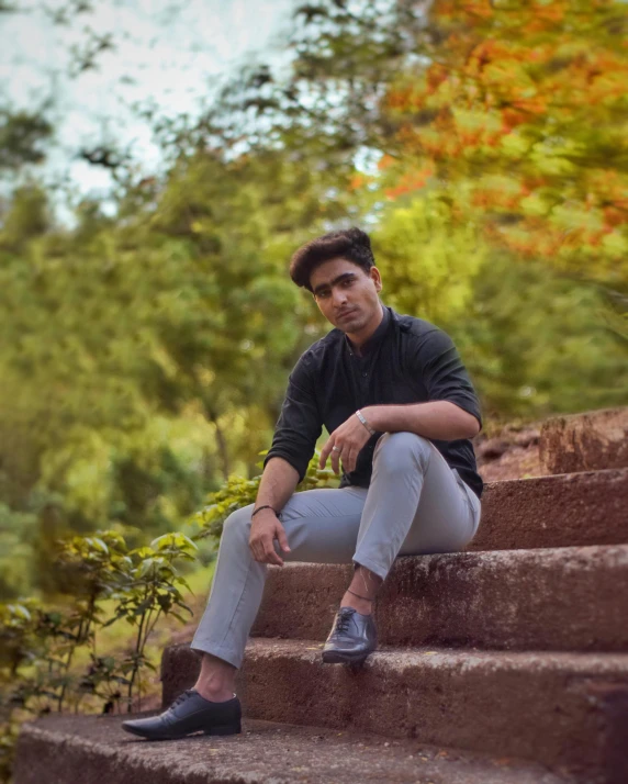 man sitting on a step outside in a black shirt