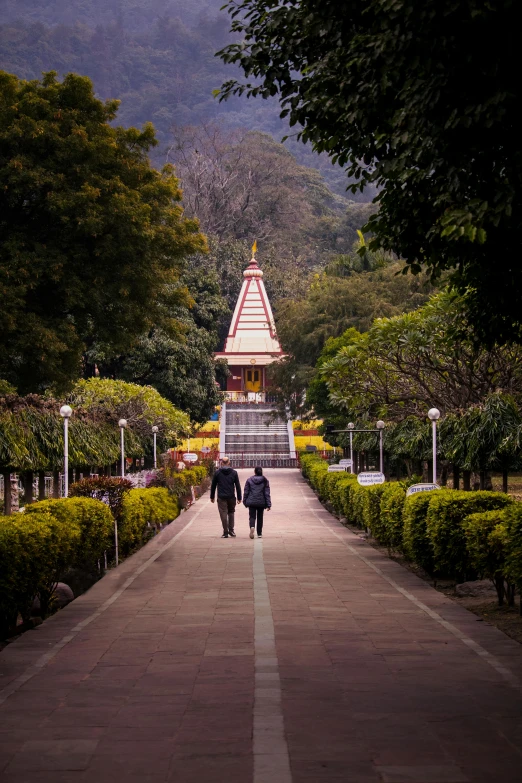 a large group of people walk down a path towards a temple