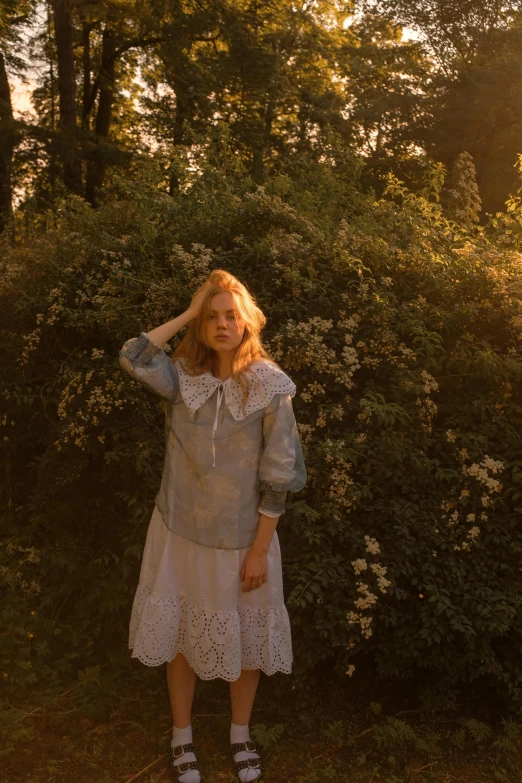 the girl stands in a white dress with her hands on her head