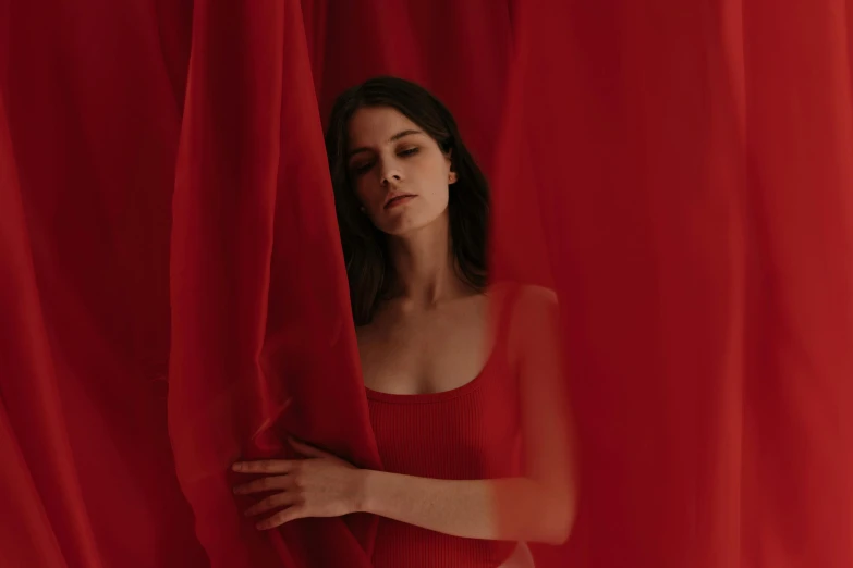 the woman is looking through a red curtain