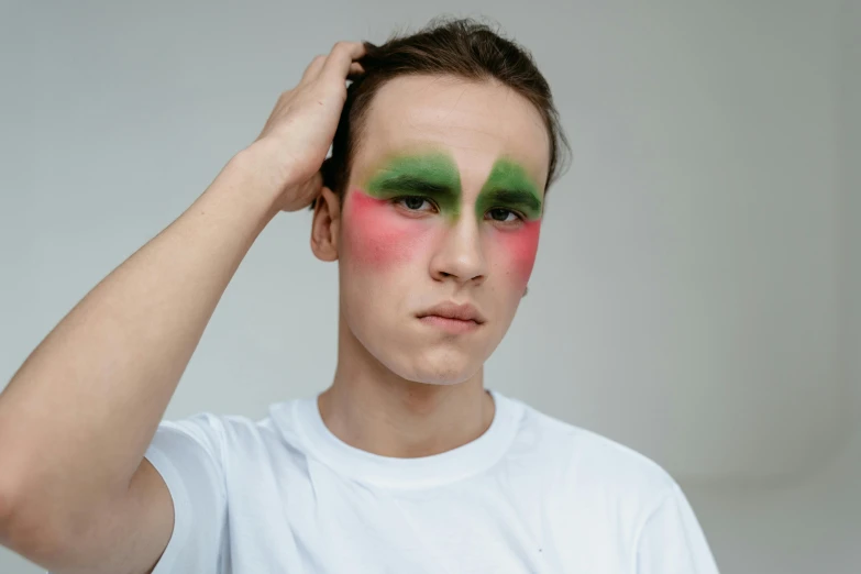 a young man with green and pink makeup