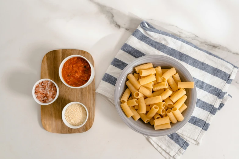 a bowl of mac and cheese sits next to a plate of sauce