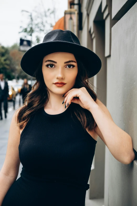 a woman wearing a hat stands next to the street