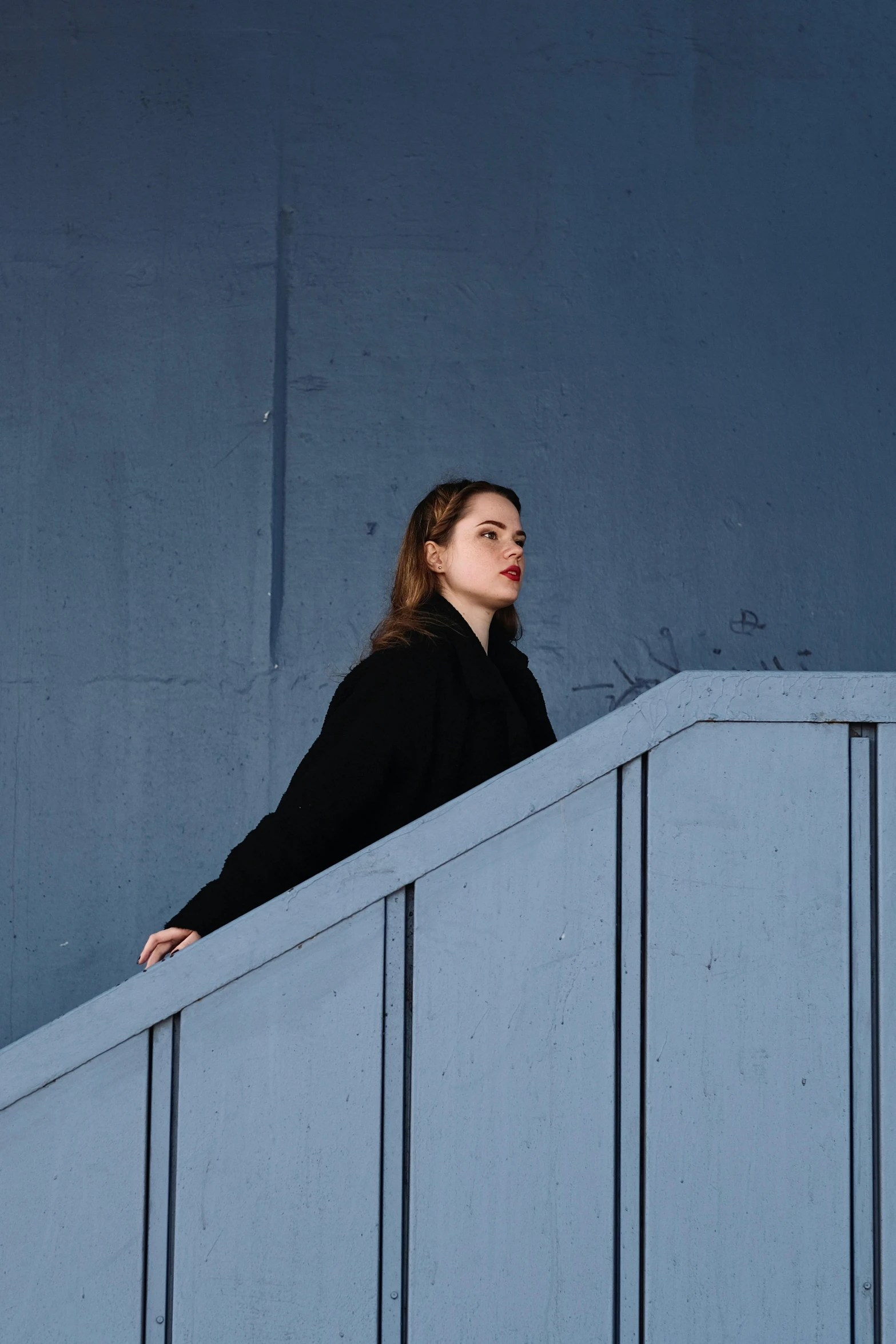 a woman in black leaning up against a ledge