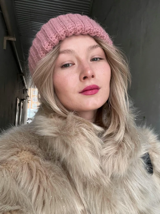 a woman wearing a pink hat and furry coat