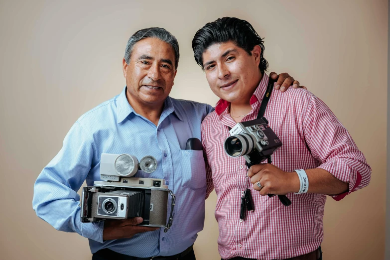 two men holding cameras while posing for a po