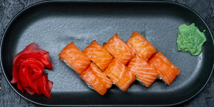 a platter with sushi, spinach and flower