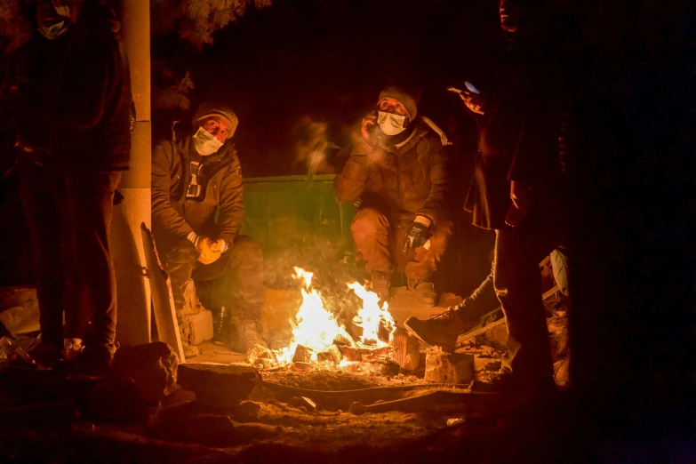 a group of people sit around a campfire