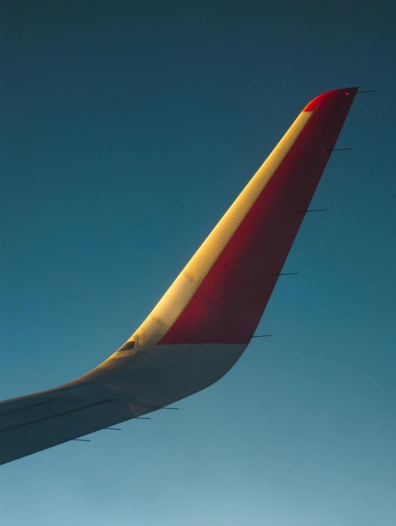 the tail of an airplane that is red and gold