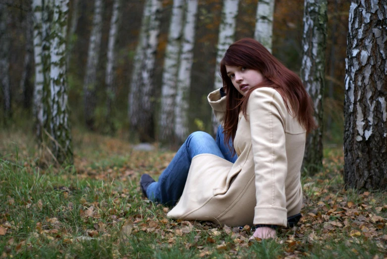 a red - haired woman with a cigarette in her mouth sitting on the ground