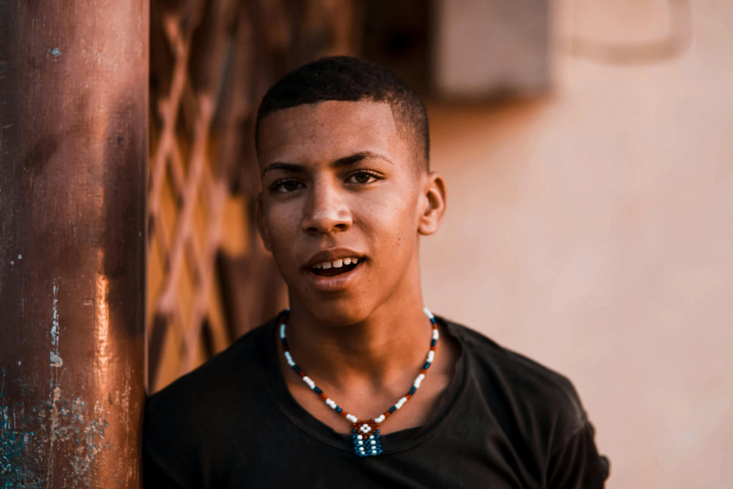 a man is posing for a picture wearing a necklace