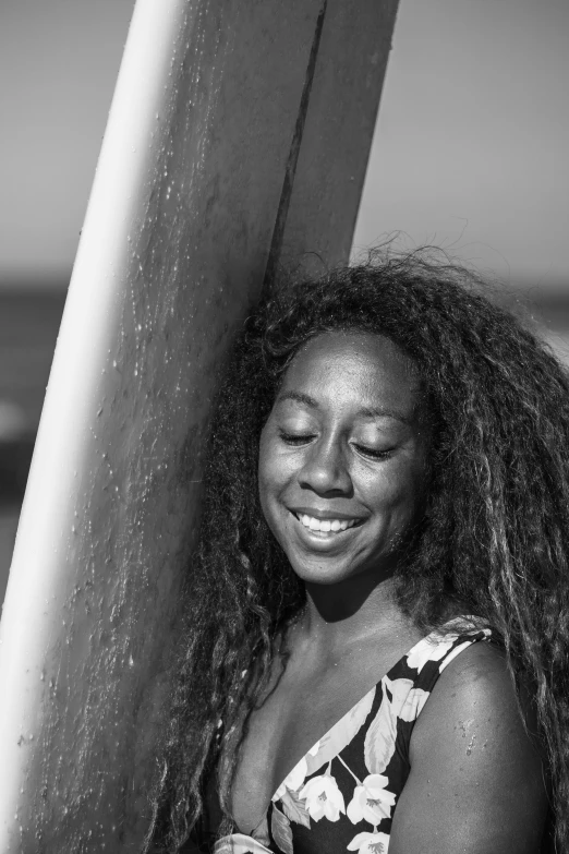 the smiling woman is standing next to the surf board