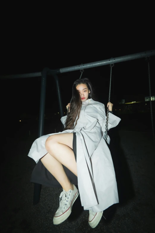 young woman sitting on swing in dark lit park area