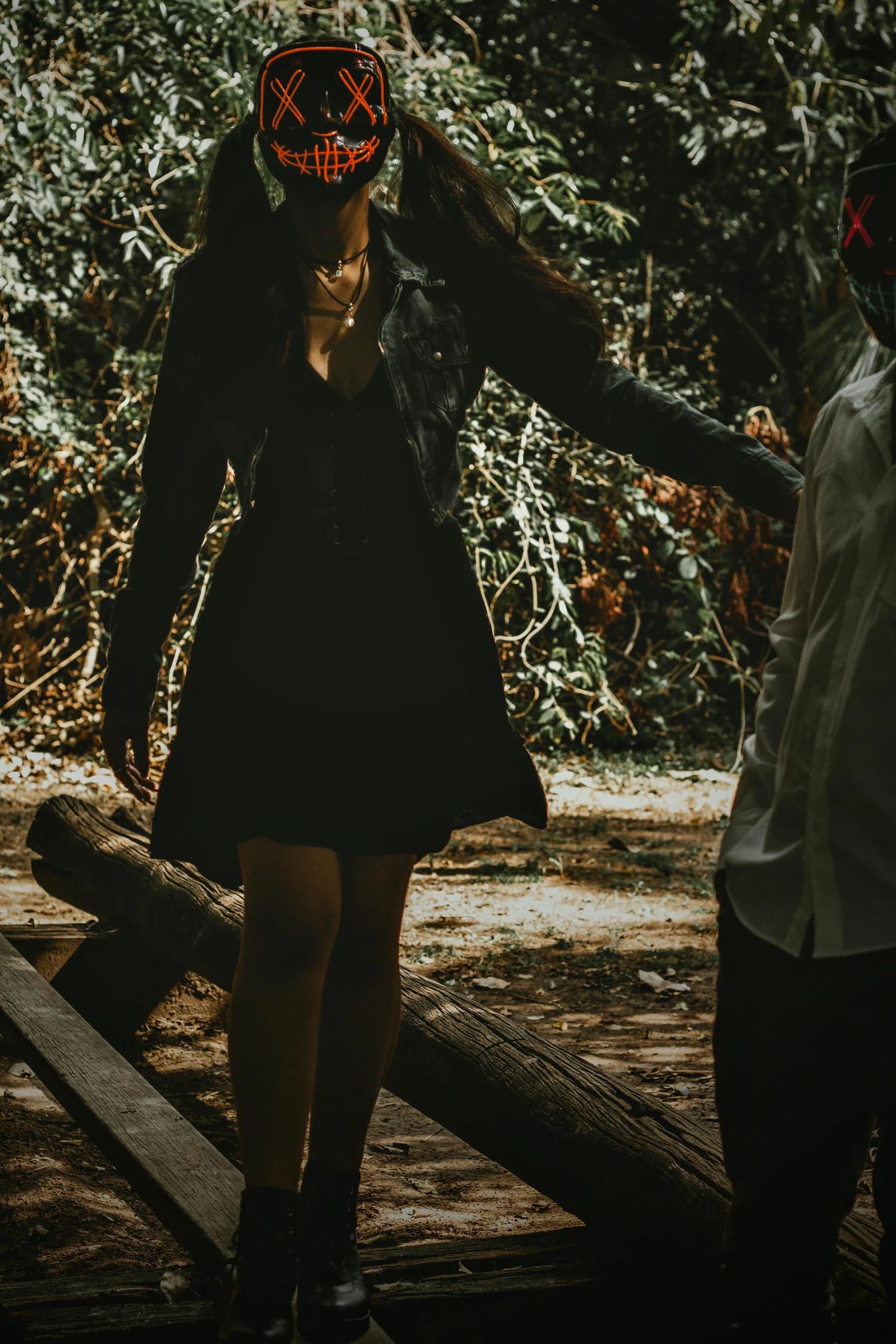 a person is in a dark forest walking in the woods with his arm wrapped around his head and an odd shaped item above their head