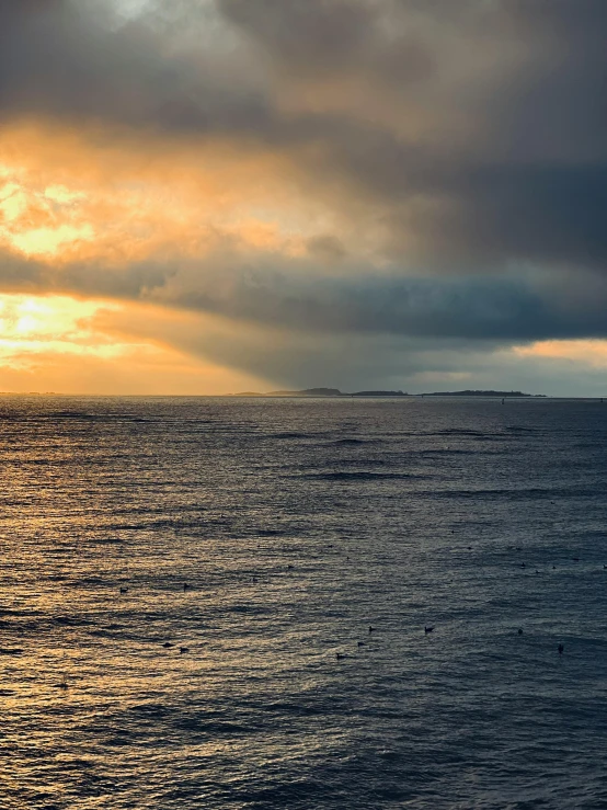 a lonely sailboat out at sea with a view of a distant island