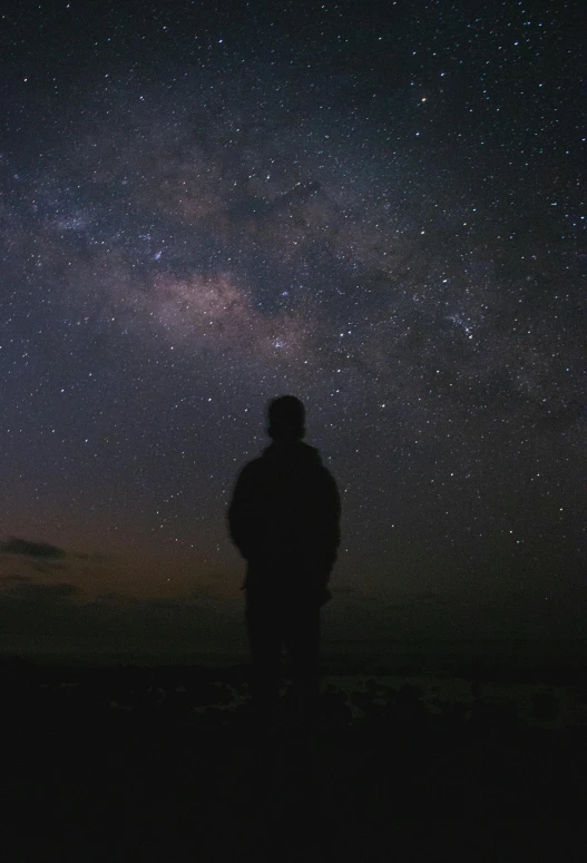 silhouette of person standing in front of stars at night