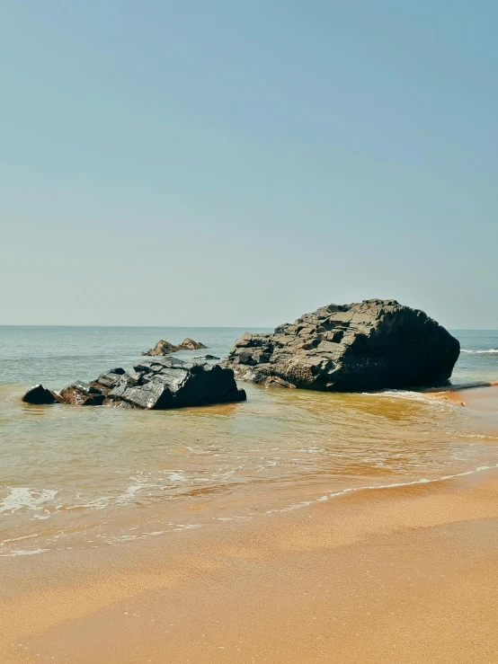 a boat traveling along the ocean side near some rocks