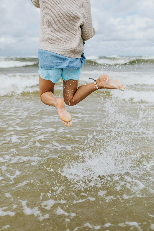 a barefoot child jumps into the surf from the water