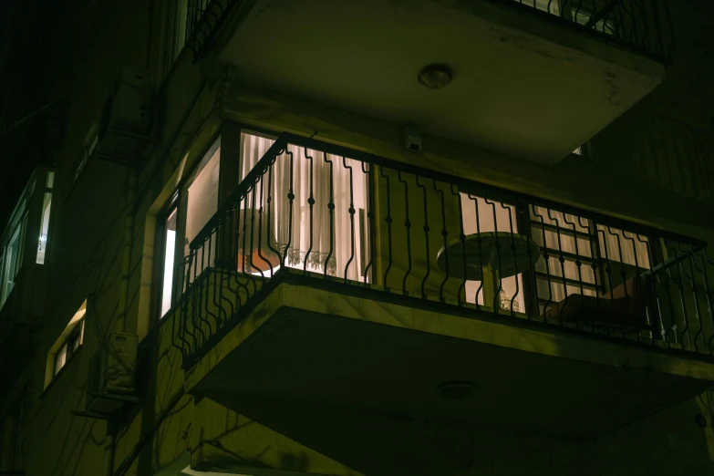 a balcony and stairway with two people sitting in the window