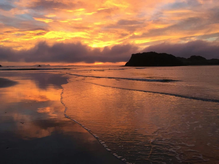 a beautiful sky is reflected on the water at the beach