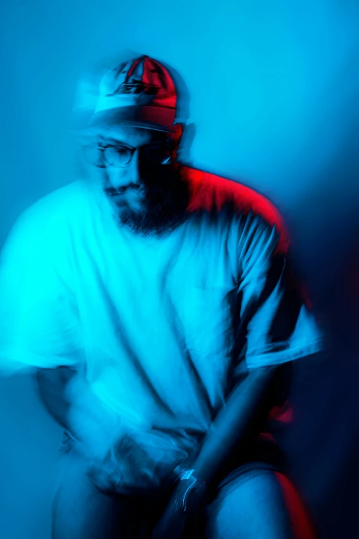 a man sitting down in front of a blue light